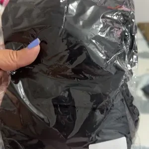 Peça preta na embalagem, segurada pela mão